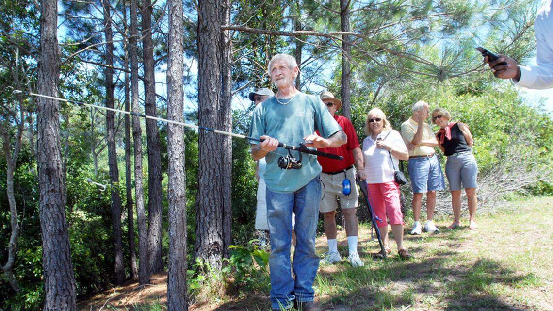 Spectators watch as Joe Maffo of Critter Management looks for a 13-foot alligator in the lake at Jarvis Creek Park on Hilton Head Island. Maffo was trying to hook the gator with a fishing rod, but it was too far away. 