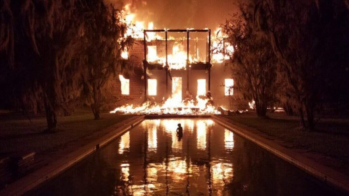 A statue in a fountain at Myrtle Grove Plantation in Colleton County is silhouetted by the three-alarm blaze that destroyed the house late Wednesday and early Thursday.