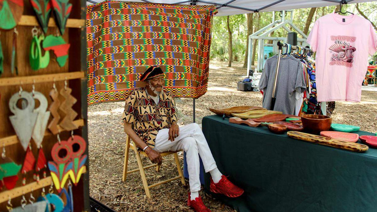 Baba Yusef, 83, sits at his stall at Mitchelville’s Juneteenth celebration on Hilton Head Island on June 14, 2025. Yusef carves wooden bowls and incense holds, a craft he learned in West Africa.