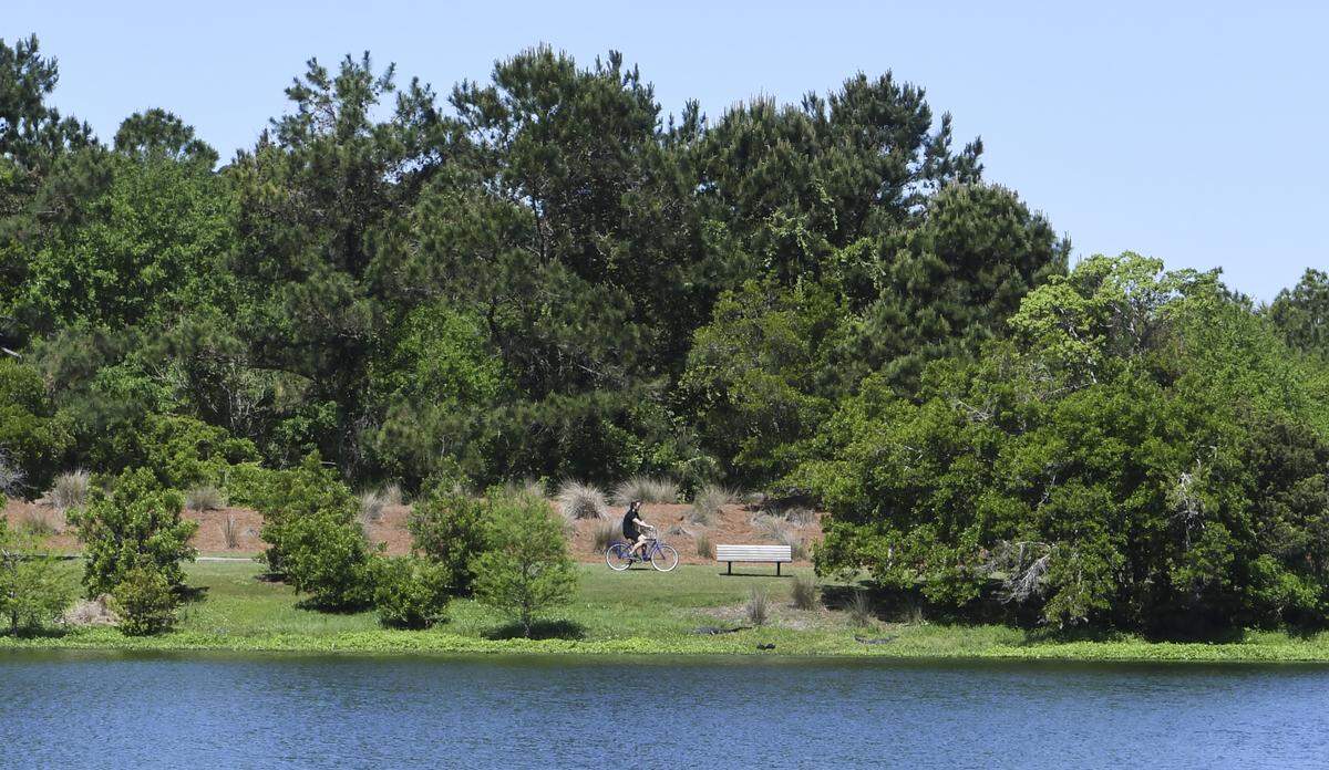 A lone biker pedals around the lake at Jarvis Creek Park on Thursday, April 2, 2020 after S.C. Gov. Henry McMaster closed all beaches and parks in hopes of stemming the spread of the coronavirus.