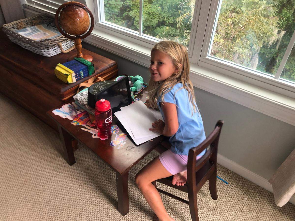 Harper Smith, 6, at her desk in her family’s guest bedroom on her first day of first grade at Hilton Head School for the Creative Arts. She works on her school-provided iPad with the help of her parents.