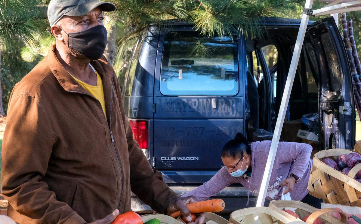 Carolina Seafood & Produce’s Wesley Campbell talks to a customer at Hilton Head Farmers Market as his wife Carrie, background, pulls together produce to give to food banks on the island on Tuesday, Nov. 17, 2020 on the grounds of Coastal Discovery Museum on Hilton Head Island. “We normally do 100 but this week we’re doing 50.” Carrie Campbell said as she grabbed bananas from a cluster. Their seafood and produce stand, a daily fixture at Squire Pope Road and U.S. 278, had to be dismantled after the town of Hilton Head Island purchased the land in August.