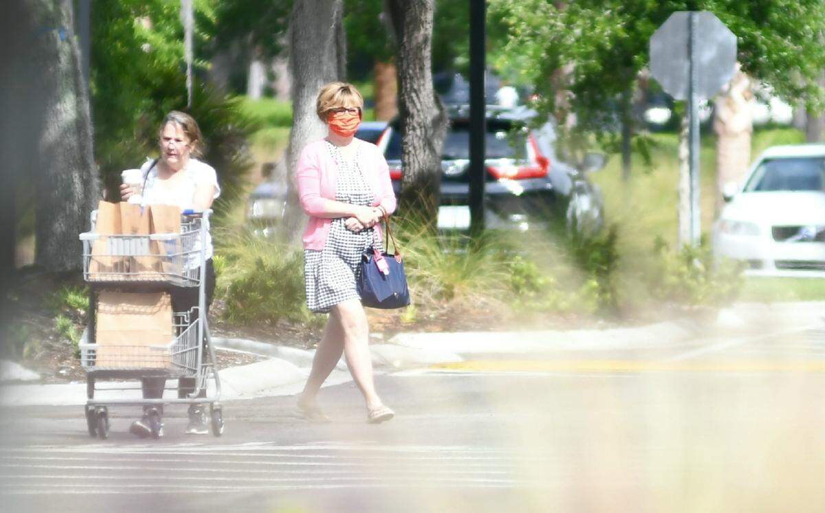 One shopper leaves the Kroger at Belfair Commons in Bluffton on Thursday, April 30. Another, wearing a cloth mask, walks to the entrance. The town of Bluffton is asking residents to wear masks when shopping in public.