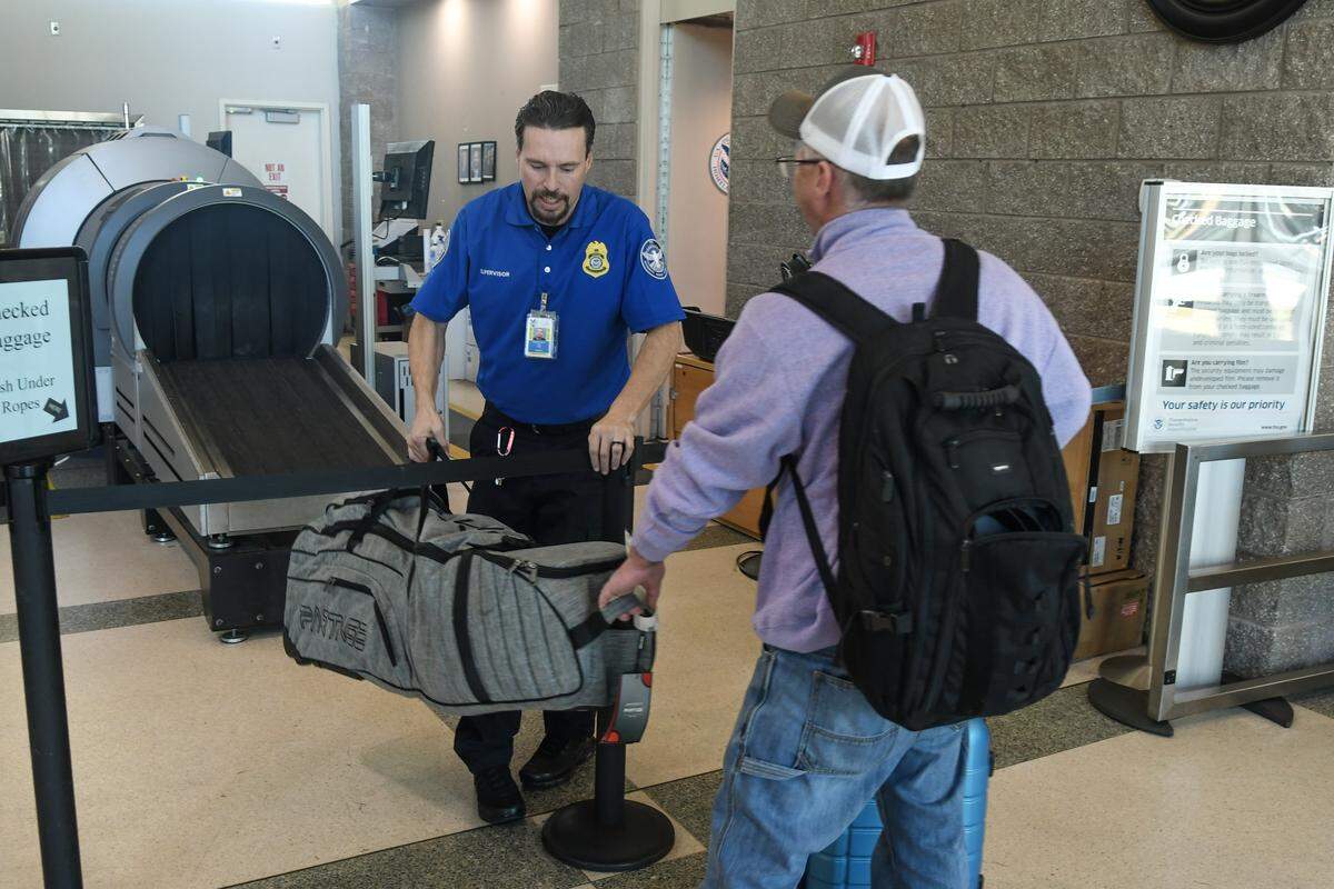 Benjamin Woods, left, a supervisor with the Transportation Security Administration, is handed a set of golf clubs by a passenger for it to be scanned on Nov. 17, 2025 at Hilton Head Island Airport.