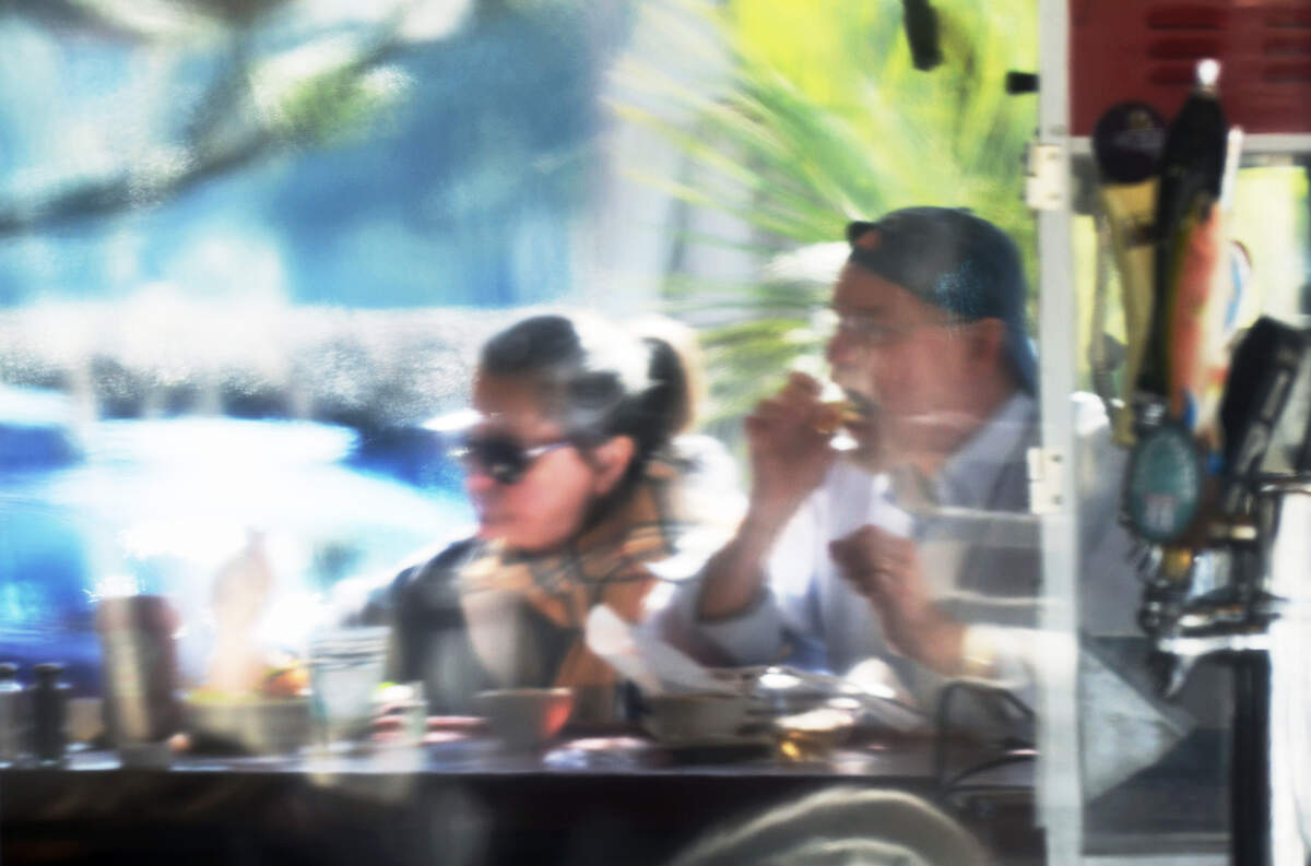 A couple eating lunch at the Salty Dog Cafe on Hilton Head are photographed through a clear plastic partition that protects the outdoor bar from the elements on Friday.