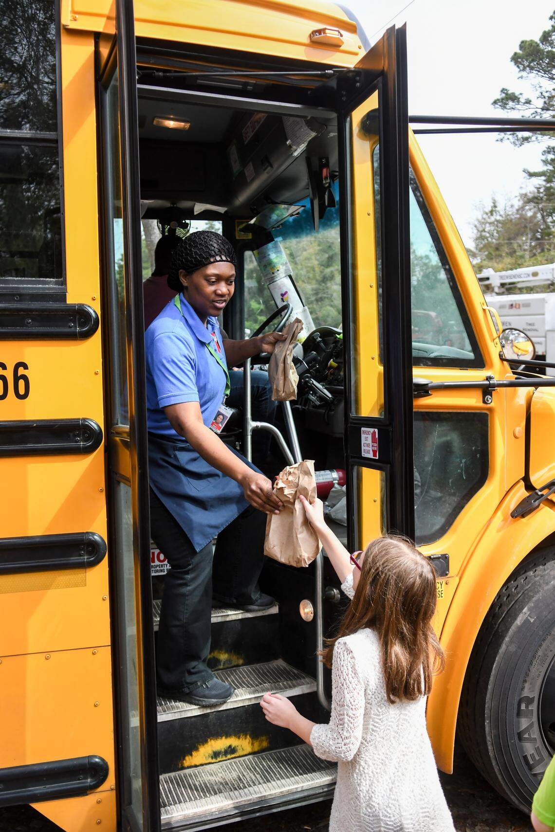 In this file photo, Sodexo employee Kendra Alston hands a student a lunch at a bus stop on Tuesday, March 17, 2020 in Bluffton on Crestwood and Shad avenues. The Beaufort County School District added several mobile bus stops throughout the county to deliver food during the COVID-19 pandemic for families with transportation issues.