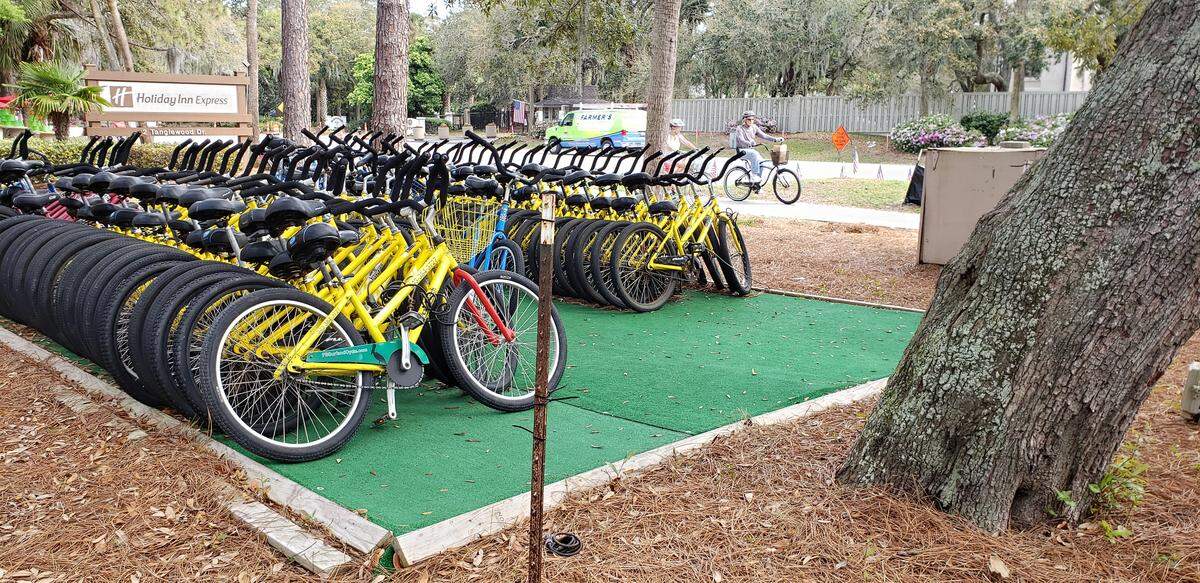 Bikers pedal past bundles of bikes ready to be rented in front of the Holiday Inn Express on Tuesday, March 17, 2020 on South Forest Beach Drive on Hilton Head Island.