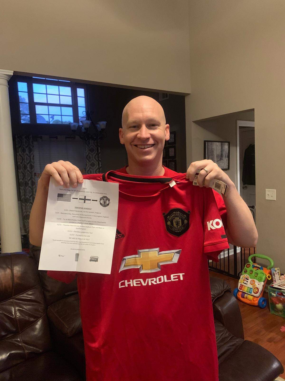 John Burk with his Manchester United jersey and trip itinerary to London and Manchester, England that his soccer club planned to celebrate his cancer remission.