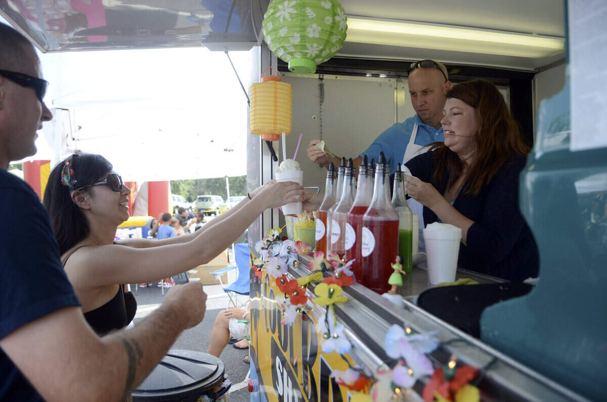 Ashley Miller, right, with Cool Breeze Shaved Ice, hands a shaved ice to Camille Cunningham of Beaufort on Saturday during the inaugural Beaufort Food Truck Fest hosted by ARTworks at the Beaufort Town Center Pavilion in Beaufort.