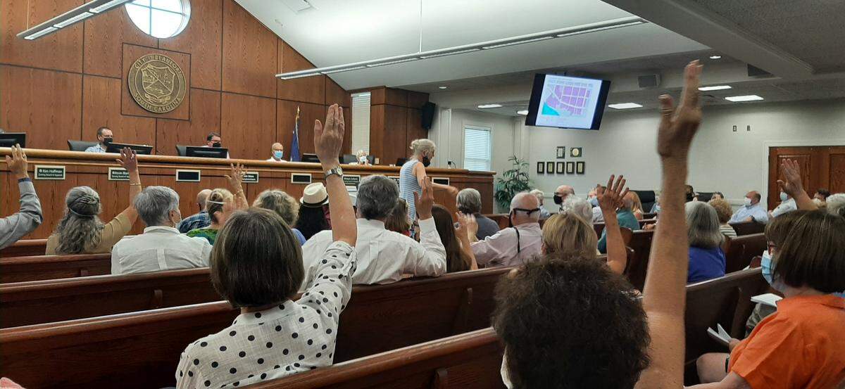 Opponents of an apartment building in downtown Beaufort raise their hands at a Zoning Board of Appeals meeting Tuesday.