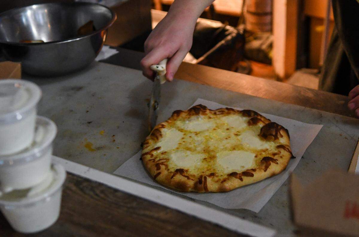 Chase Stodghill prepares to slice “The Monkey” on Friday, March 10, 2023, at Local Pie, a restaurant located in The Promenade in Bluffton. The pizza consists of a garlic olive oil base with mozzarella, ricotta, parmesan and local herbs.