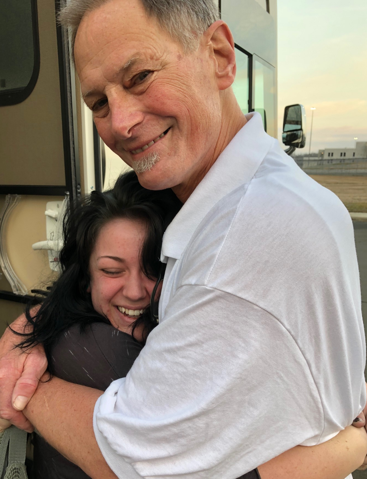 Drew Dobson hugged by his granddaughter, Finley, immediately after walking out of the Federal Correctional Institution in Butner, North Carolina, seen in the background.