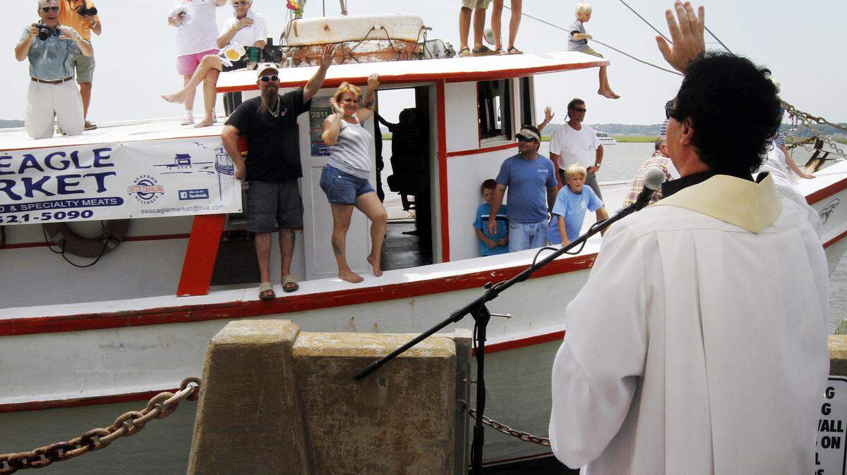 Father Paul MacNeil of St. Peter's Catholic Church on Lady's Island, right, waves Sunday after blessing the Gracie Belle shrimp boat. The 59th Beaufort Water Festival wrapped up with the Blessing of the Fleet and Parade of Boats at Henry C. Chambers Waterfront Park.