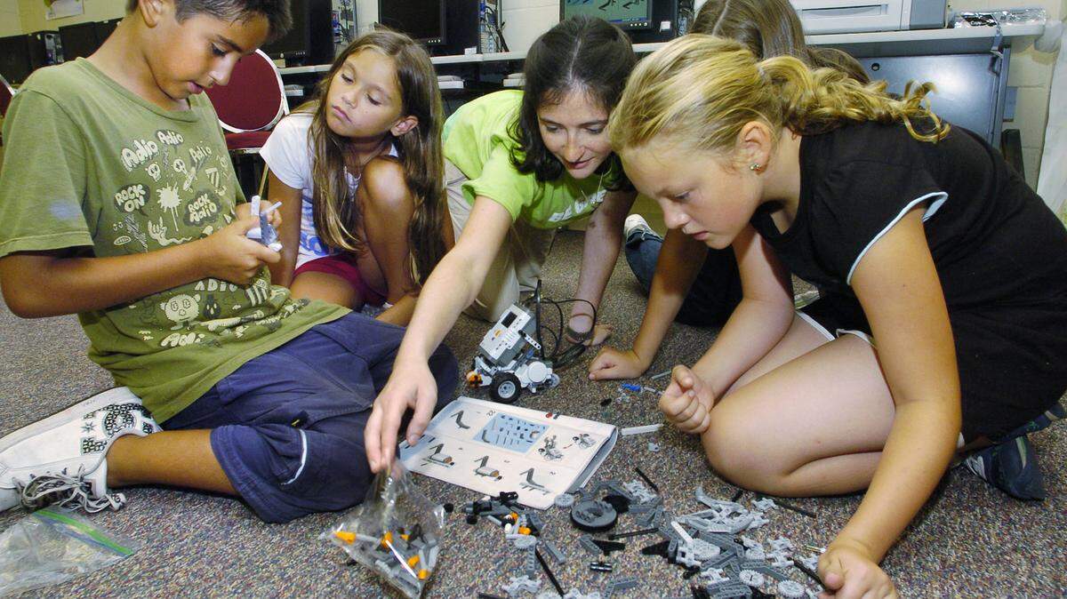 From left, Hilton Head Boys and Girls Club kids Pablo Ahumada, 10, Kaelee Mucha, 9, teacher Abi Fidler and Olivia MacIsaac, 9, sift through spare parts in search of the right piece as they assemble a bumper with a touch sensor for their Lego Mindstorms NXT robot, visible at center, at the club on Tuesday.