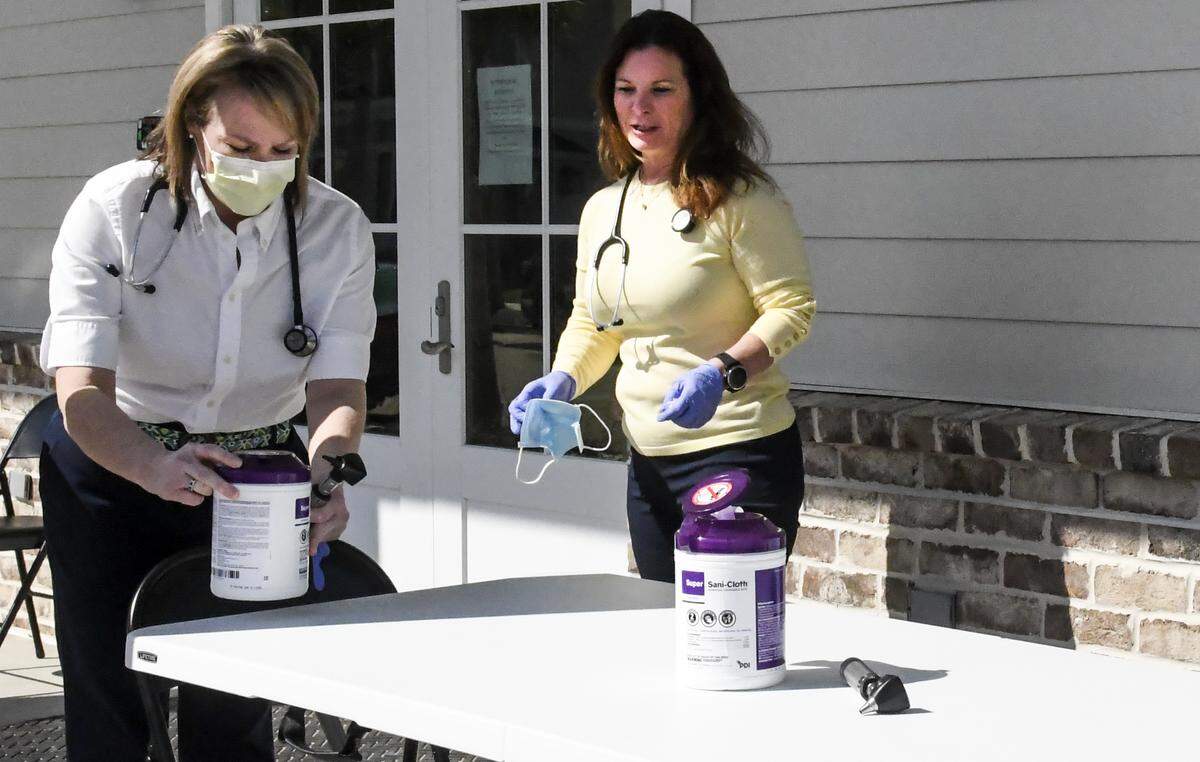 Kimberly Stockstill, NP, left, and Jennifer Green, NP use medical-grade wipes to sanitize the table at Bluffton’s Affordable Healthcare on Thursday, March 12, 2020 after a patient visit. Green, owner of the care facility, said they got the idea to see patients outside after seeing hospitals use triage centers in parking lots. If patients have symptoms comparable to coronavirus, they give patients a mask and send them to the health department. “We don’t have (coronavirus) testing kits,” Green said but stressed that 99% of patients likely have the flu or severe allergies from pollen.