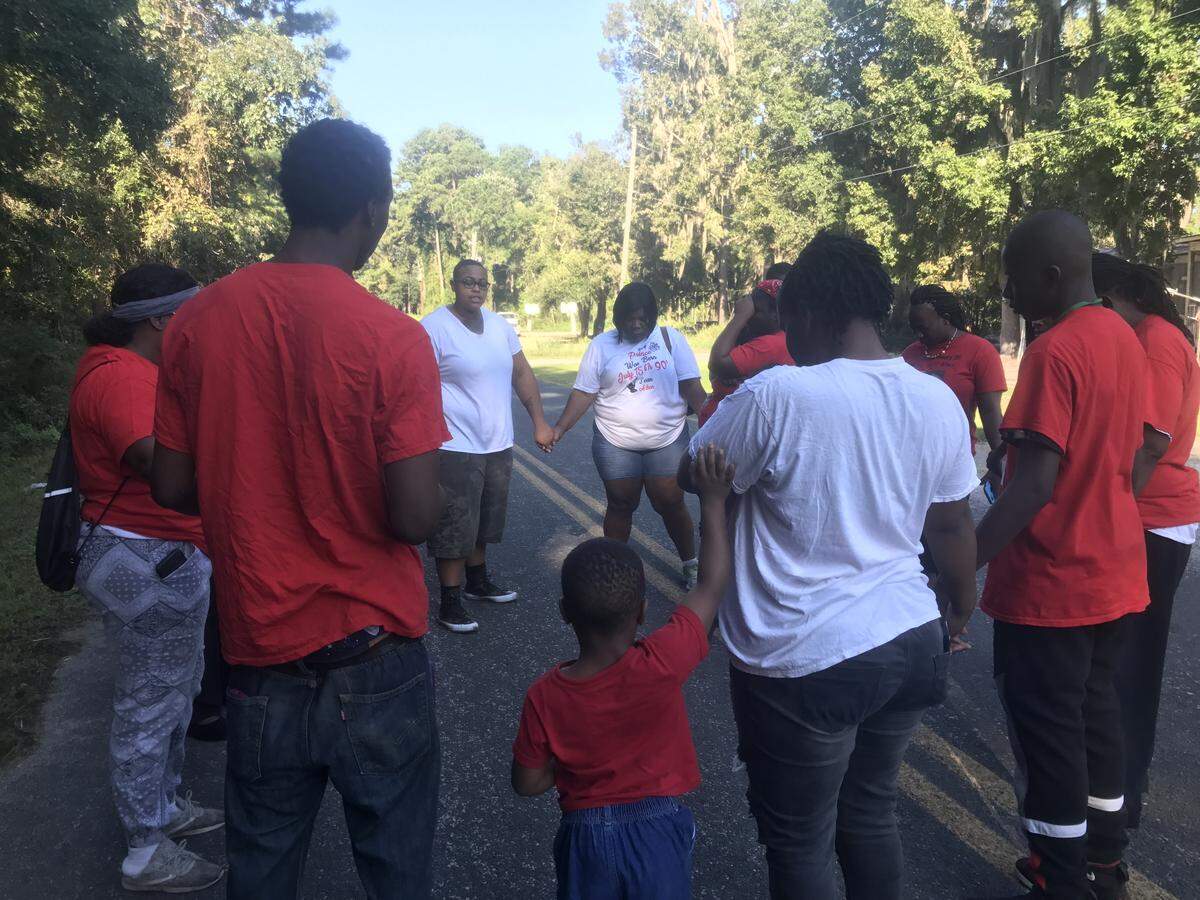 Family and friends pray at the start of a rally against violence in memory of Sean Aiken.