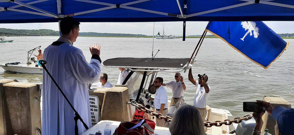 Mayor Stephen Murray pilots a boat carrying City Council members as Father Andrew Trapp blesses the fleet Sunday.