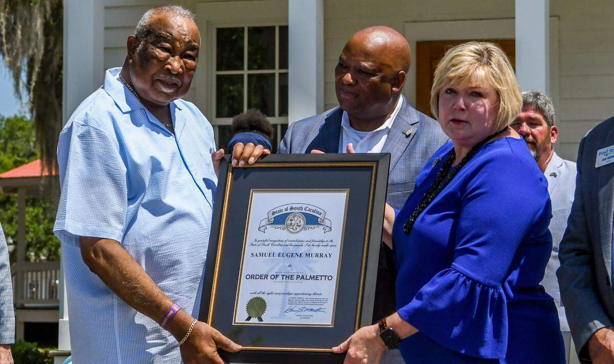 In a surprise announcement on Friday, June 10, 2022, state Rep. Shannon Erickson, right, and state Sen. Gerald Malloy, center, present former Town of Port Royal Mayor Sam Murray with the state’s highest honor, the Order of the Palmetto. Murray retired in 2019 after 41 years of public service, first as a councilman and then as mayor since 1995. He died Saturday.