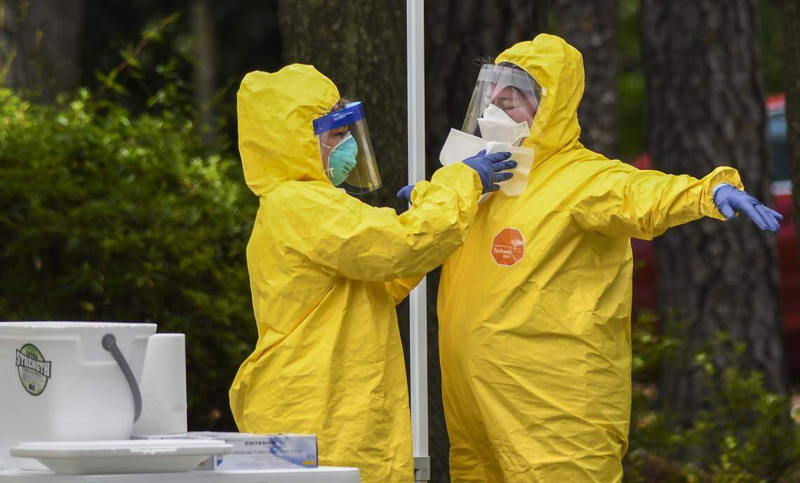 A worker uses disinfectant wipes to clean the personal protective equipment of a worker who just administered a nose swab at the free COVID-19 test site on Thursday, May 28, 2020 at the Elijah Washington Medical Center in Sheldon.
