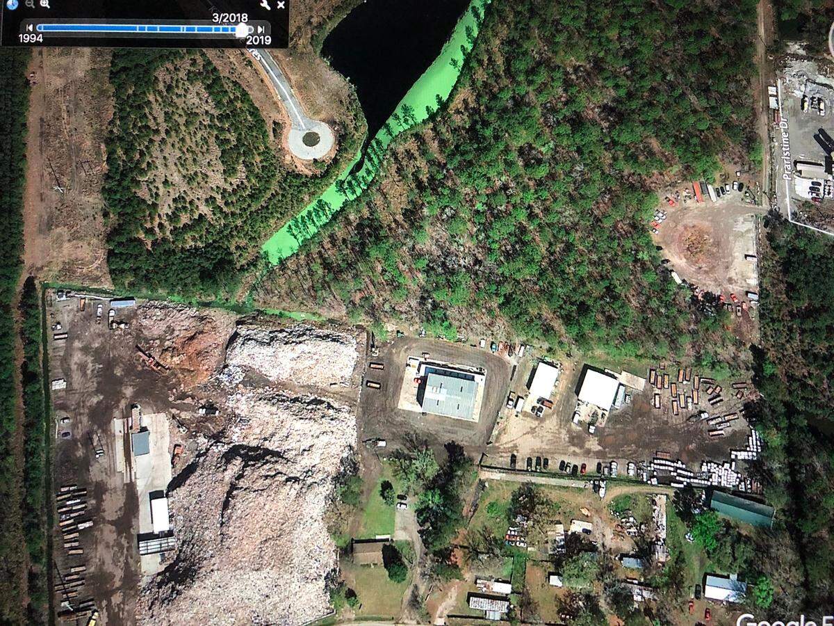 A screenshot of a Google Earth photograph from March 2018 shows the Able Contracting property and the surrounding drainage ditch and retention pond. A fluorescent green layer of bacteria and nutrients is visible in the water.