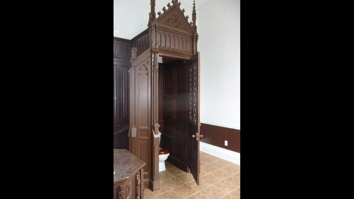 A toilet in a Rose Hill Mansion bathroom is surrounded by ornate woodwork.