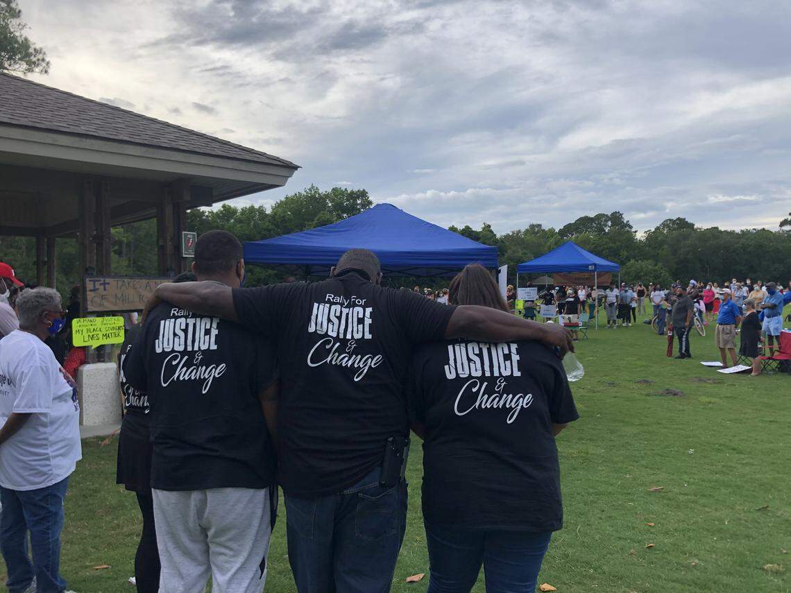 Organizer Galen Miller places his arms over others, including his daughter, as the Rally for Justice and Change observes 8 minutes and 46 seconds of silence for George Floyd on Sunday, June 7.