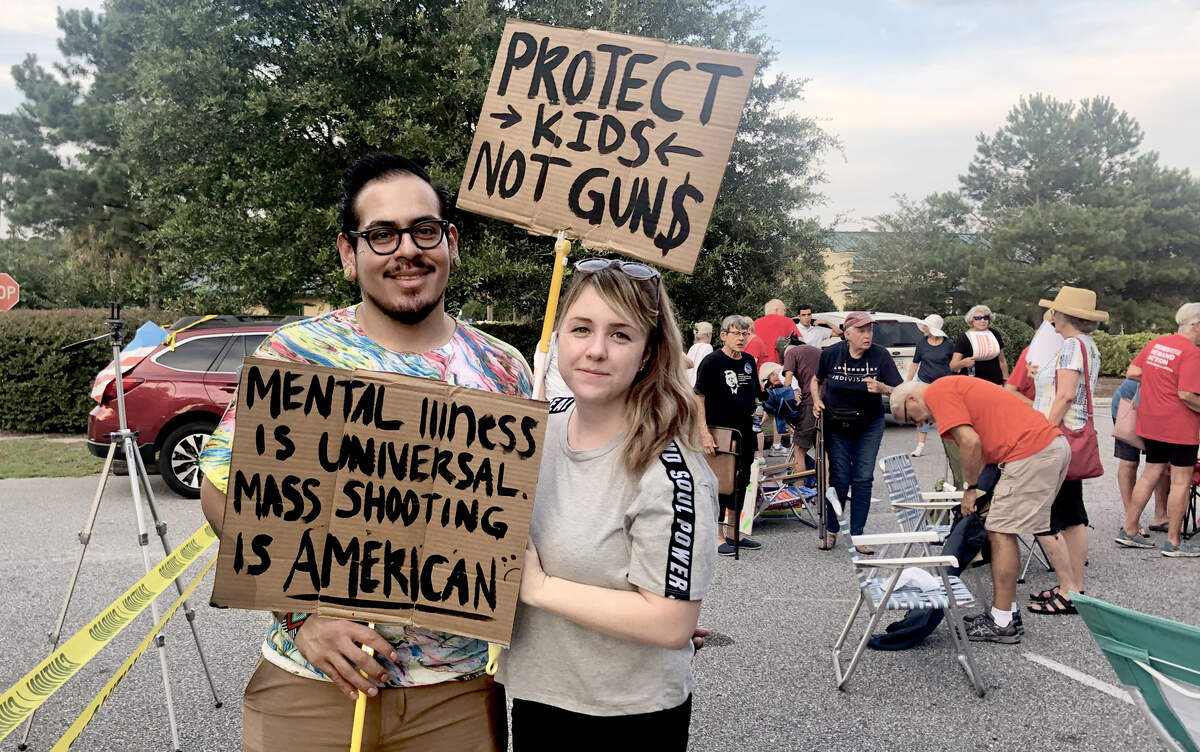 Jeanne Coston and Daniel Aranza hold signs on Aug. 8 at a vigil for 31 people who died over the weekend in mass shootings in El Paso, Texas and Dayton, Ohio. The vigil was also a gun violence protest.