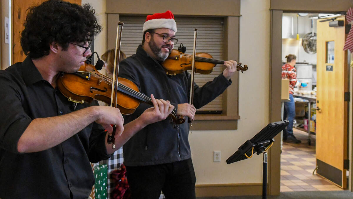Volunteers work in the kitchen on Friday, Dec. 20, 2024, as Jesús Parra, center, and his son, Jesús, a student at Hilton Head Island High School, serenade those at St. Andrew By-The-Sea United Methodist Church’s Soup Kitchen on Hilton Head Island.
