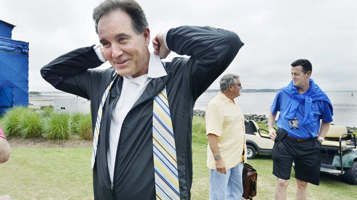 Standing behind the 18th green, CBS sports announcer Jim Nantz slips on his tie before heading up to the CBS kybox broadcast booth to begin the network's coverage of the third round of the RBC Heritage Presented by Boeing golf tournament on Saturday.