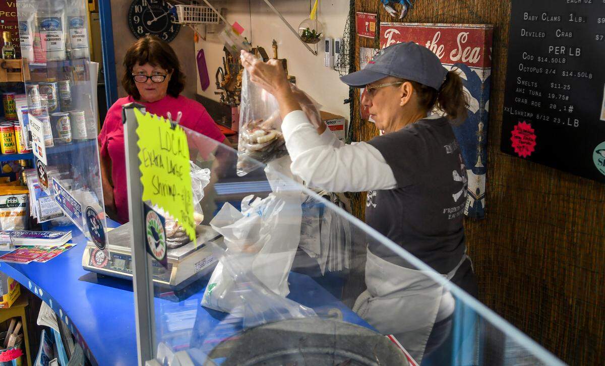 Janice Heuck, left, watches as fellow employee Colleen Wooby weighs out locally caught shrimp for a customer on Friday, March 24, 2023 at Benny Hudson Seafood on Hilton Head Island.