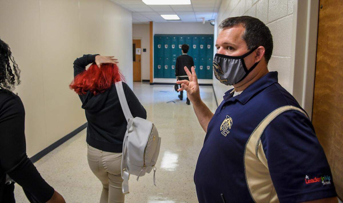 Chad Cox, principal of Battery Creek High School, waves to the students as they change classes during the hybrid re-opening of the school on Oct. 5. 2020 due to the coronavirus pandemic.