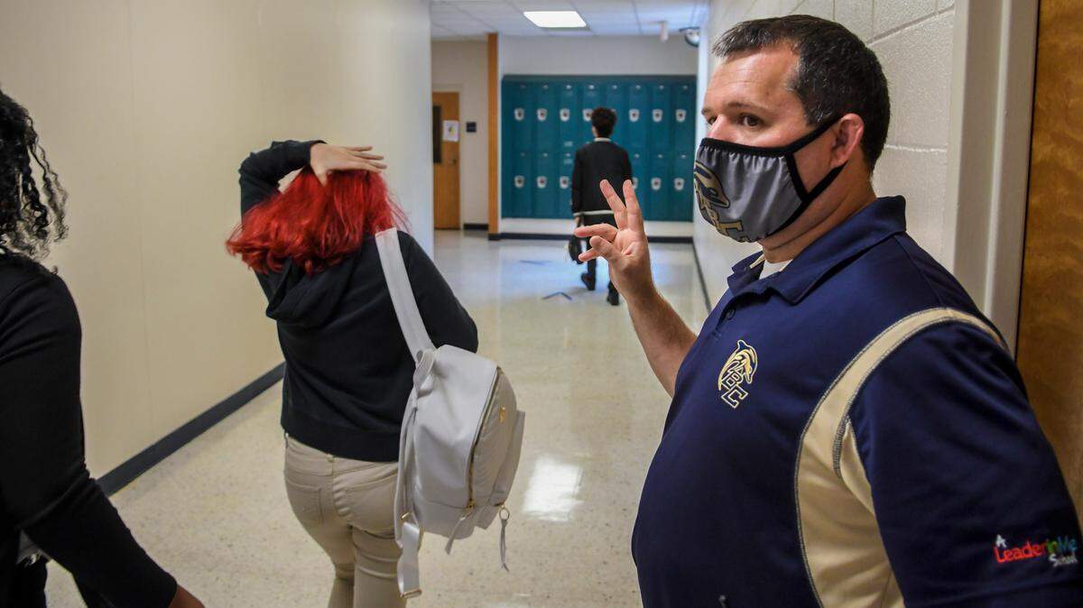 In this file photo, Chad Cox, then-principal of Battery Creek High School, waves to the students as they change classes during the hybrid re-opening of the school on Oct. 5. 2020 due to the coronavirus pandemic.