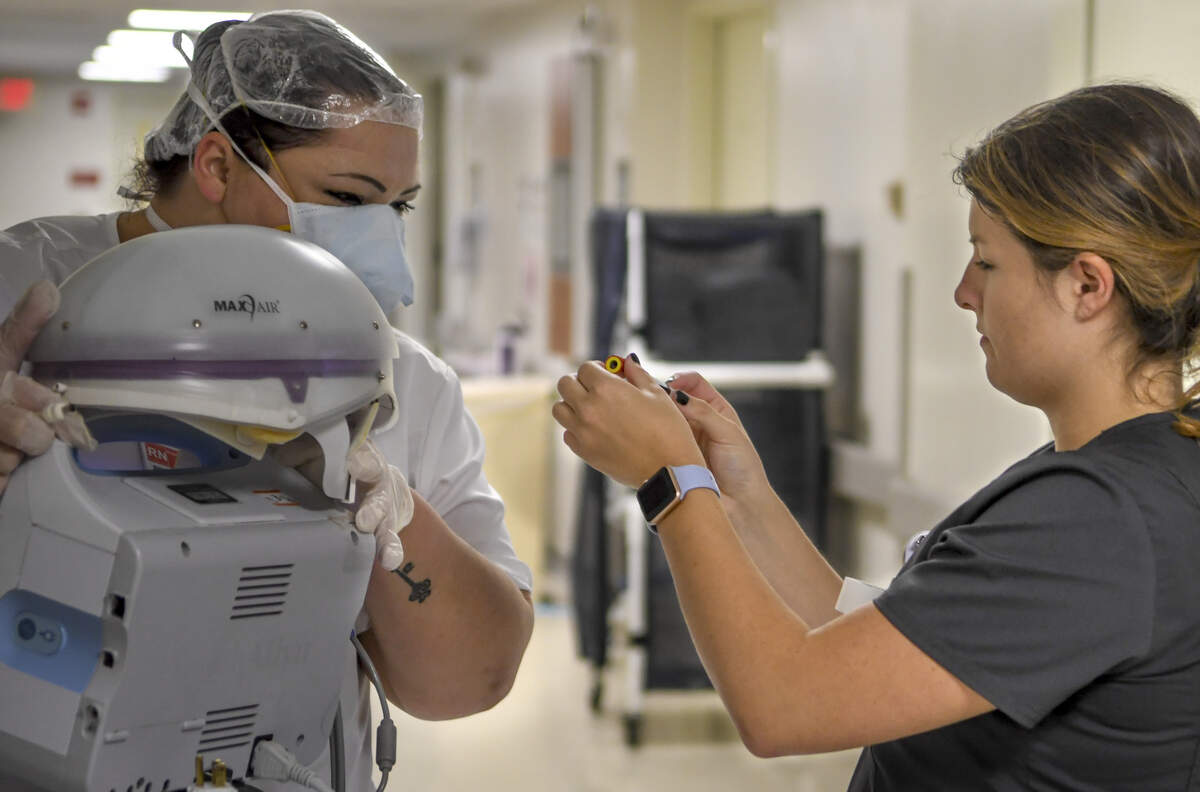 April Simmons-Smith, RN, left, verifies the labeling on the vial held by Bailee Lott, right, a nurse intern on April 16, 2020 at Beaufort Memorial Hospital. Simmons-Smith, after spending more than 30 minutes with a patient in full protective protective equipment, asked for Lott’s help with labeling as Simmons-Smith had to return to the patients room to administer additional care.