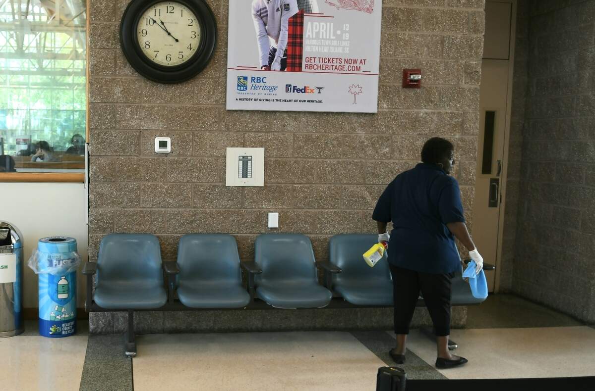 A worker sanitizes empty chairs on Thursday, March 26, 2020, at Hilton Head Island Airport in the barren waiting area.