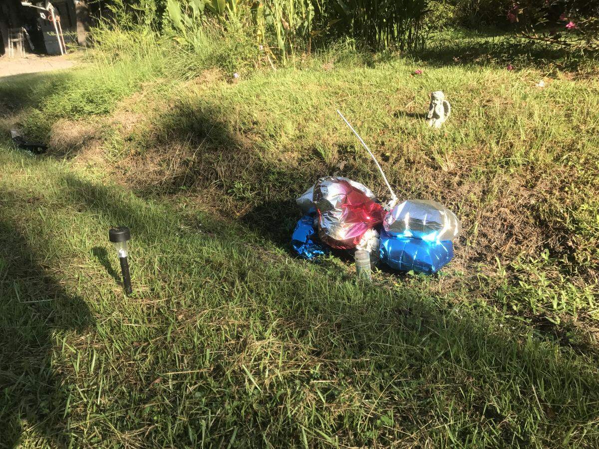 Balloons sit in the ditch where Sean Aiken’s body was found.