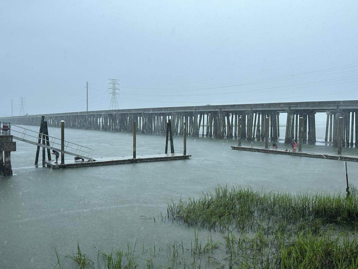 A family and a sole angler fish in the rain at the C. C. Haigh, Jr. Boat Landing dock beside the Hilton Head Island bridge on Aug. 30, 2023 during a hurricane warning issued for Hurricane Idalia.