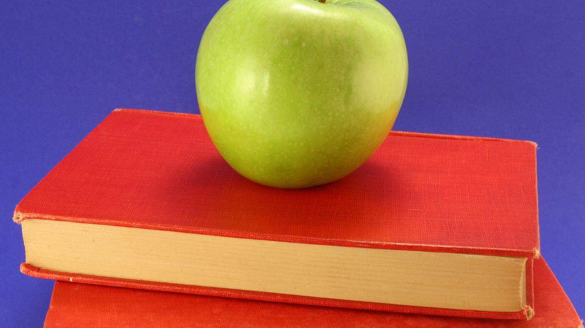 Green apple on stack of red books.