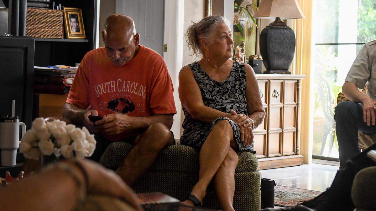While Matt Lewis, left, looks up data on his smartphone his wife, Kim Lewis, center, talks with her neighbors on July 29, 2025, about the Town of Hilton Head Island granting building permits to new construction for what they fear will become short term rentals in their Holiday Homes neighborhood on Hilton Head.