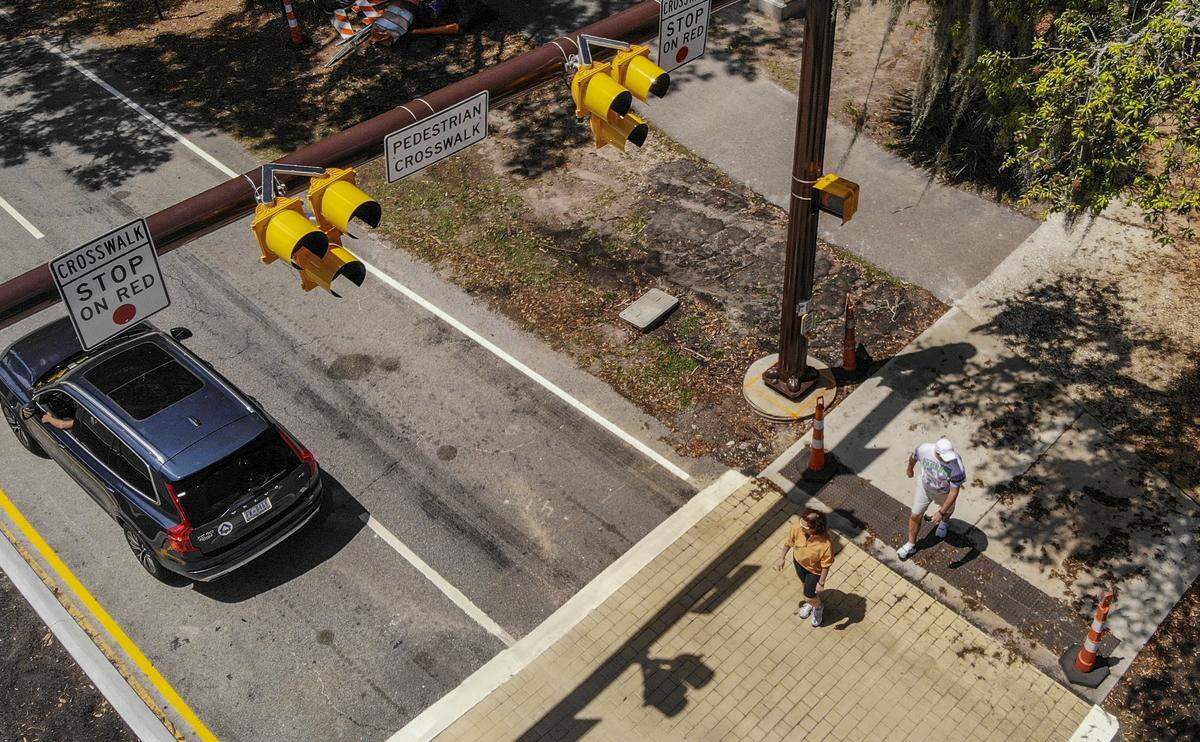 Pedestrians cross South Forest Beach Drive just past Coligny traffic circle, where the town of Hilton Head Island installed a crosswalk safety device on Monday, April 20, 2020. While Coligny Beach Park remains closed by the Town of Hilton Head Island in response to the coronavirus pandemic, the High-Intensity Activated Crosswalk is expected to keep pedestrians more safe when tourists return. To activate the signal, pedestrians press a button that activates an overhead light that flashes yellow, warning drivers the light is about to turn red. The light then turns solid yellow and then red for cars to stop, and a “walk” symbol is displayed, alerting pedestrians to cross. After 30 seconds, the light goes dark, allowing traffic to resume.