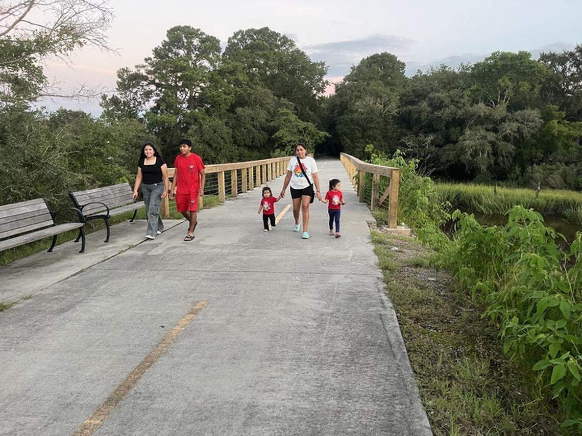 A family enjoys a walk on the northern end of the Spanish Moss Trail near Albergotti Creek. From left to right: Christel Bernal, Edwin Milla and Aleida Milla, who is holding the hands of children Dailyn Argueta and Camila Argueta.