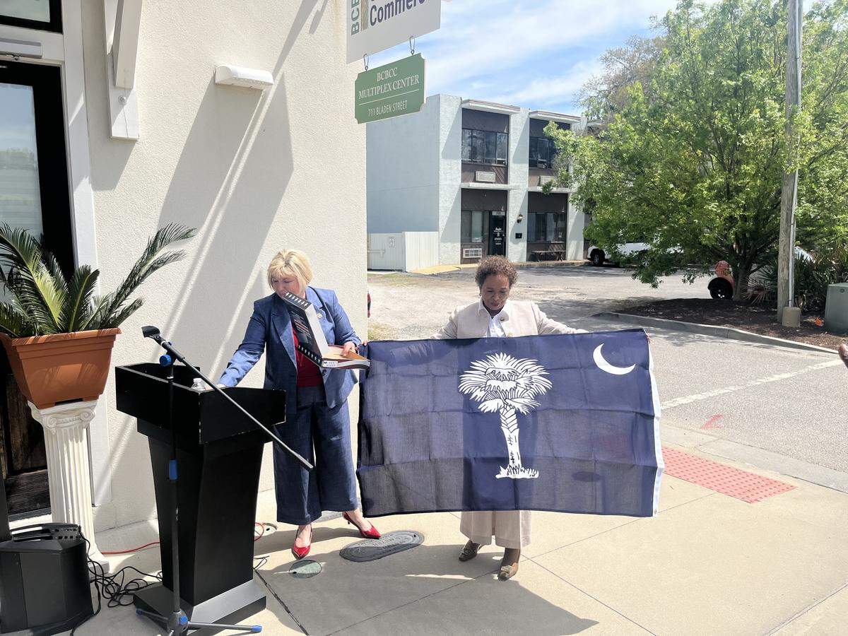State Rep. Shannon Erickson left, presents Marilyn Harris, executive director of the BCBCC Center for Culture and Commerce, with a brand new state flag to mark the new name and mission of the agency.