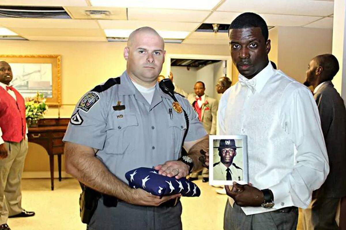 SC Highway Patrol Lance Cpl. James Sweatman, left, holds an American flag and Kevin Smalls, a corporal in the Colleton County Sheriff's Office, holds a photo of his father, SC Highway Patrol Trooper First Class Bruce K. Smalls. The men were photographed at Smalls' wedding on Sept. 27, 2014, exactly 29 years after Bruce Smalls' father was gunned down on the side of Interstate 95 in Hardeeville by a man in a stolen RV.