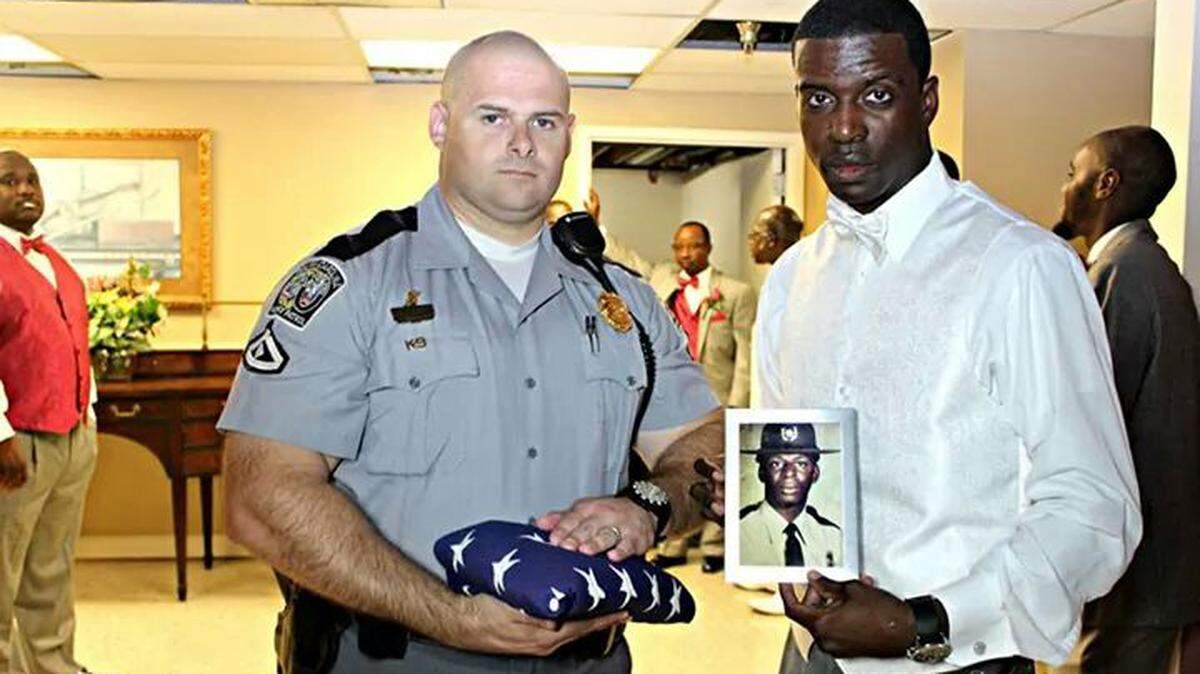 SC Highway Patrol Lance Cpl. James Sweatman, left, holds an American flag and Kevin Smalls, a corporal in the Colleton County Sheriff's Office, holds a photo of his father, SC Highway Patrol Trooper First Class Bruce K. Smalls. The men were photographed at Smalls' wedding on Sept. 27, 2014, exactly 29 years after Bruce Smalls' father was gunned down on the side of Interstate 95 in Hardeeville by a man in a stolen RV.