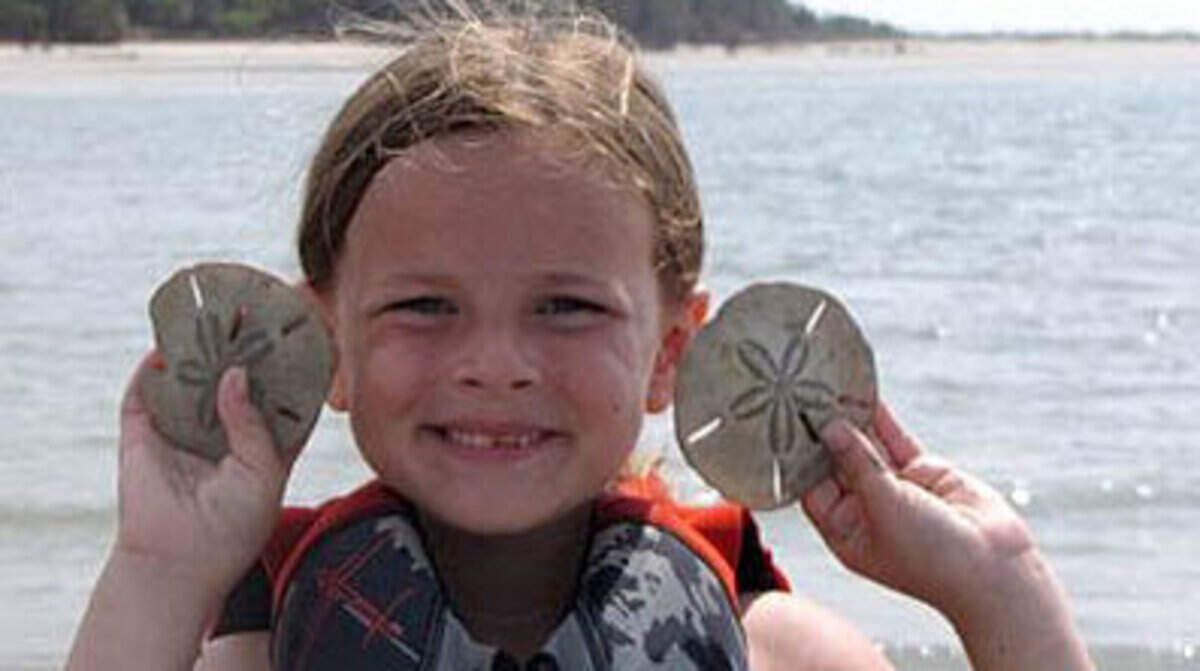 Gracie Packard, 6, holds up sand dollars she found in the area. Sand dollars are living creatures. Biologists recommend that people return them to the water. However, the creatures’  skeletons, which turn white when exposed to the elements, are fair game as keepsakes. Photo by R.C. Van Essendelft of Beaufort.