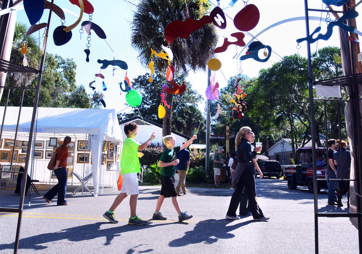 Festival goers walk past mobiles made by Bluffton artist Stephen Kishel on display at the Art and Seafood Street Fest in Old Town Bluffton on Saturday. The event, featuring and art show, Lowcountry cuisine and musical entertainment, is part of the week-long 11th Annual Historic Bluffton Arts and Seafood Festival. Street Fest continues from 10 a.m. to 4 p.m. on Sunday.