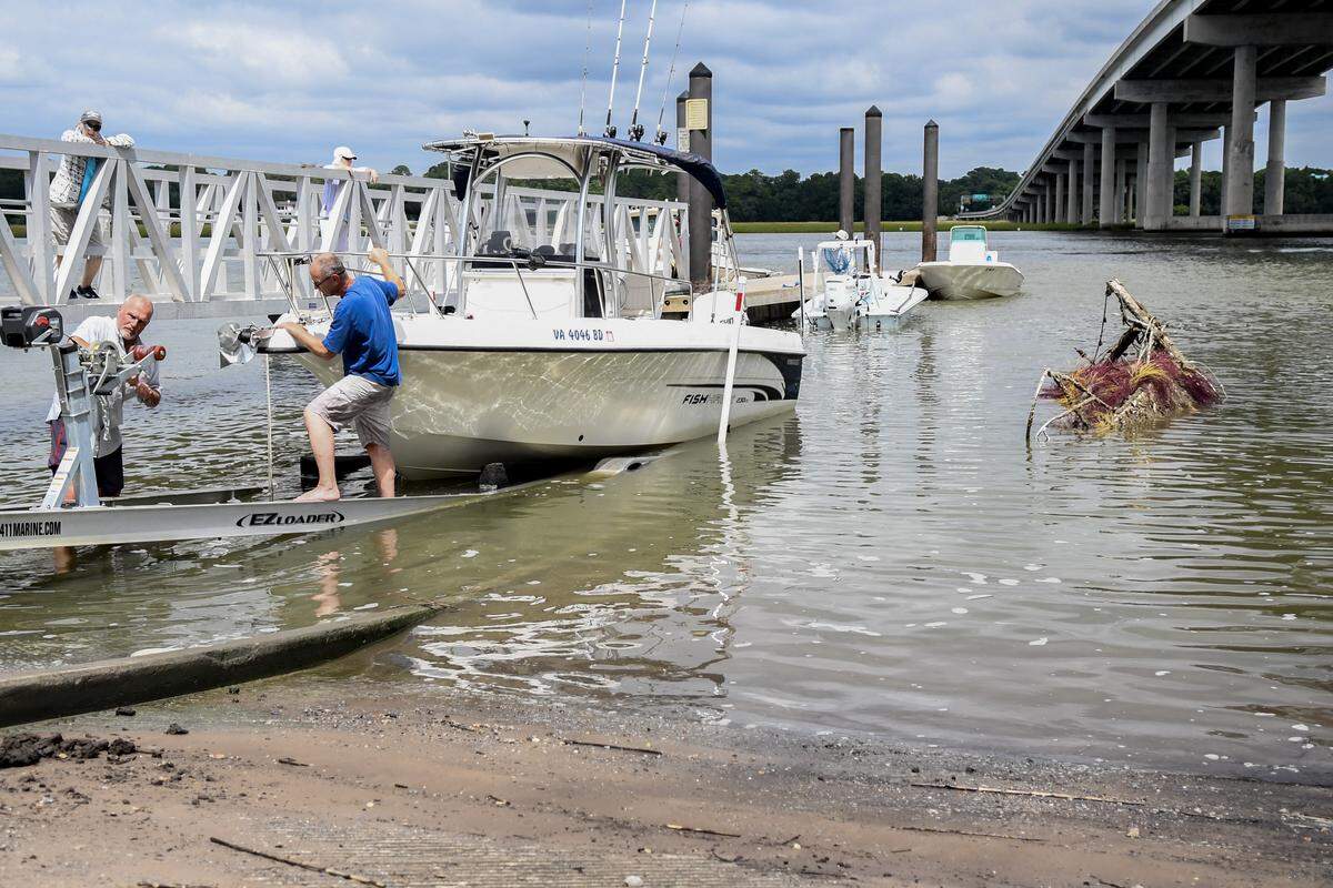 Boaters negotiate the wreckage of a sailboat, right, on Sept. 10, 2025, at the Cross Island Boat Landing that was floated and pulled to the shore by the S.C. Department of Natural Resources on Hilton Head Island. The Town of Hilton Head Island, Beaufort County and SCDNR have removed at least 10 abandoned or derelict boats from the waters of Hilton Head in the past few months.