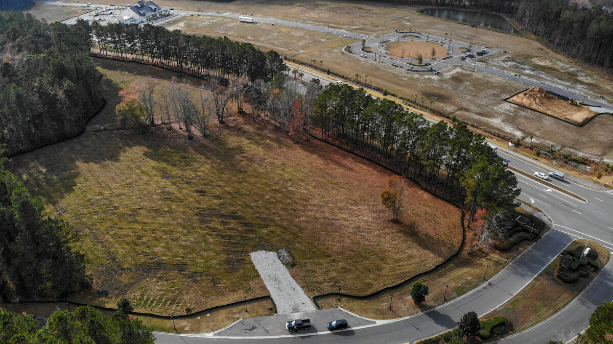 Behind a tree lined buffer fronting Buckwalter Parkway at the entrance to Woodbridge as seen on Dec. 8, 2021 sits a cleared plot of land for the May River Marketplace - a marketplace and music venue - in Bluffton.