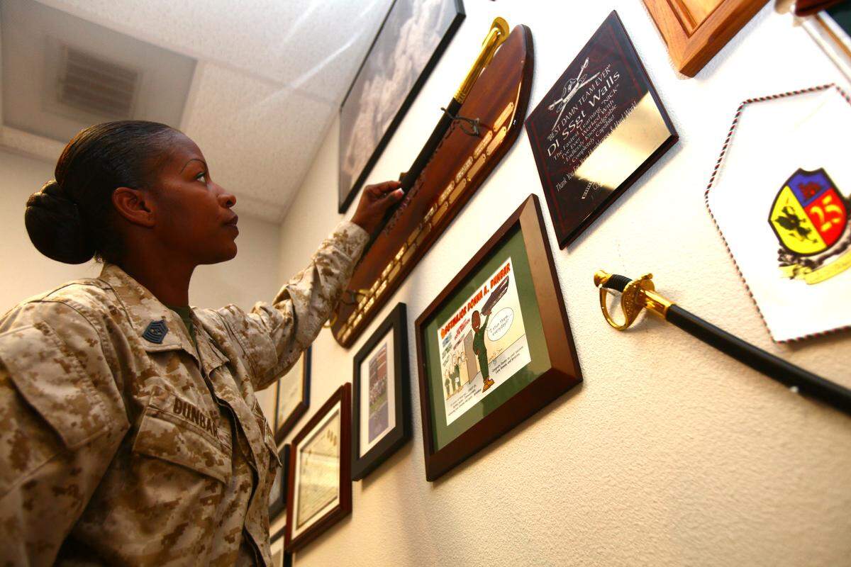 Sgt. Maj. Donna Dunbar adjusts a sword displayed on the wall of her office aboard Marine Corps Air Station Camp Pendleton, Calif., in 2013.