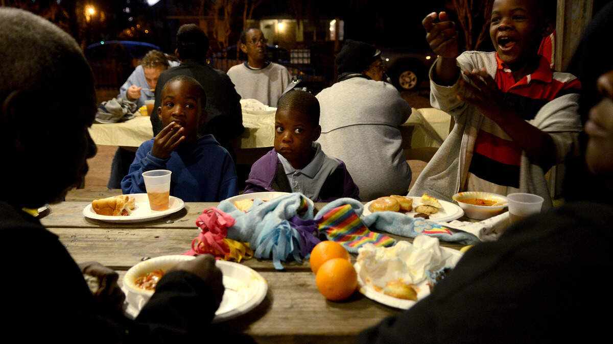 Brothers Dameon Smalls, 7, left, Khalil Brisbane, 5, center, and Isaac Smalls Jr., 6, right, eat hot dogs during the volunteer run community dinner at Washington Street park on Friday night in Beaufort.  The weekly dinner celebrates its 10th anniversary on Friday.