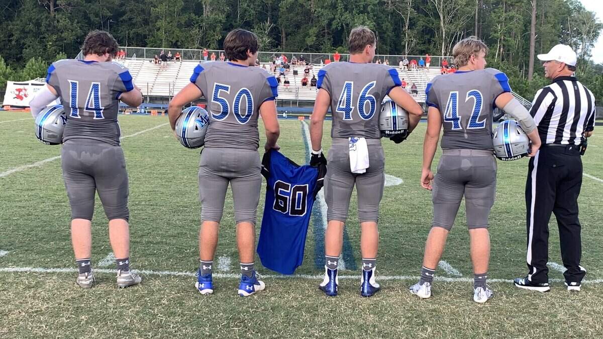 May River captains carry No. 60 jersey to midfield for the coin toss against Hartsville on Saturday. The No. 60 was in honor the number worn by Dutch Fork’s Jack Alkhatib, who died this week.
